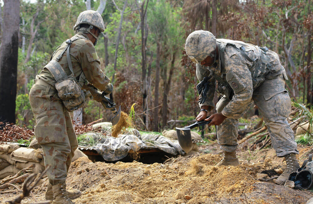 SPC Shawn Tillery and PFC Vaccine Stewart, of Alpha Company, 1st Battalion, 69th Infantry Regiment, use their entrenching tools to expand their fighting position.