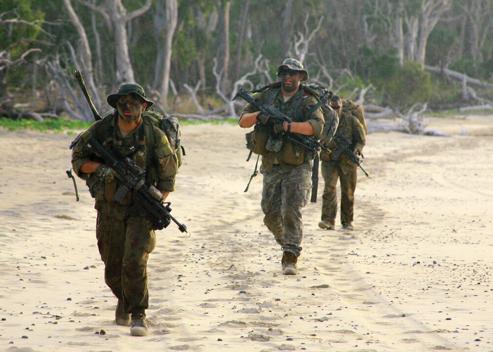 Soldiers of Charlie Troop, 2nd Battalion, 101st Cavalry Squadron, New York Army National Guard patrol along the beach wearing a mix of Australian and American uniforms as they served during the exercise, in both BLUFOR and OPFOR roles.