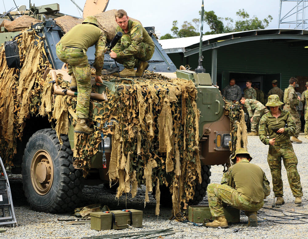 Soldiers assigned to the 1st Signal Regiment, Australian Defense Forces, attach equipment to an Australian protected mobility vehicle while preparing for the exercise.