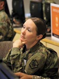 Army National Guard Soldier MAJ Christine Pierce, a defensive cyber operations team leader for the Pennsylvania National Guard's Cyber Defense element, observes a presentation during the Cyber X-Games.