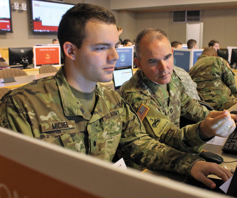 U.S. Army ROTC Cadet Brendan Michel (Left), assigned to the 1182nd Surface Deployment and Distribution Command, and his father CPT John Michel, assigned to the National Capital Region Cyber Protection Center, a unit part of ARCOG, 335th Signal Command (Theater), review training material.
