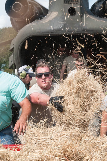 Community members and Texas National Guard Soldiers load hay onto CH-47 Chinooks for delivery to livestock left stranded by Hurricane Harvey flooding near Beaumont, Texas.