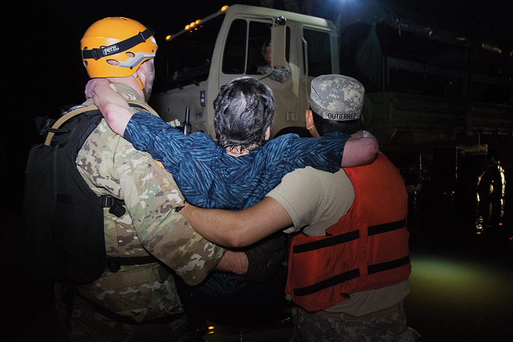 SGT Aaron Amos and SGT Eric Gutierrez of the 1-124th Cavalry Squadron, Texas Army National Guard, carry a flood victim to safety in Orange, Texas.