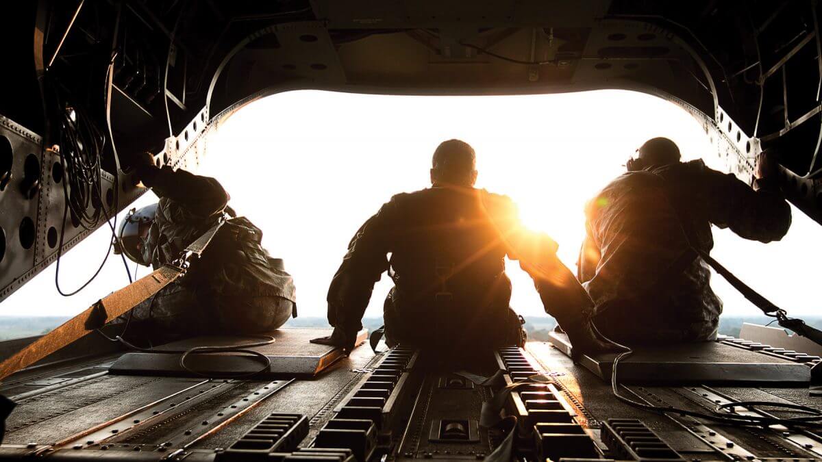 SGT First Class Roy Chandler III (left) assigned to Bravo Company, 1st Battalion, 169th Aviation Regiment, SGT Jazmin Jenkins (middle), a public affairs specialist with the 22nd Mobile Public Affairs Detachment, Fort Bragg, and SPC Benjamin Grogan (right), a helicopter repairer with the Bravo Company, 1st Battalion, 169th Aviation Regiment, sit on the tail of a CH-47 Chinook helicopter en route to deliver hay bales to cattle that have been stranded by Hurricane Harvey near Hampshire, Texas.