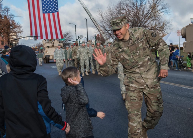 A Soldier from the Idaho National Guard at Gowen Field, “high-fives” a young spectator while participating in the 2017 Boise Veterans Day Parade in downtown Boise, Idaho. The parade theme was “Saluting the Rich Military History of Gowen Field.”