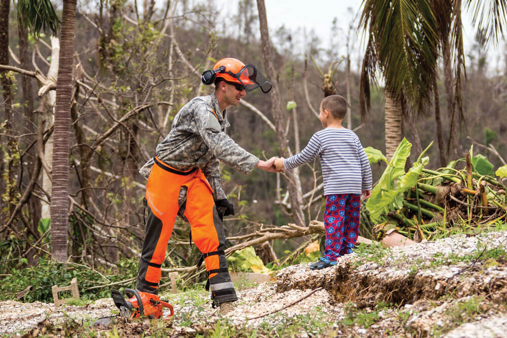 SPC Raymond Avery of Townville, South Carolina takes a break from clearing roads in Puerto Rico to say hello to a young boy in the vicinity of Cayey.