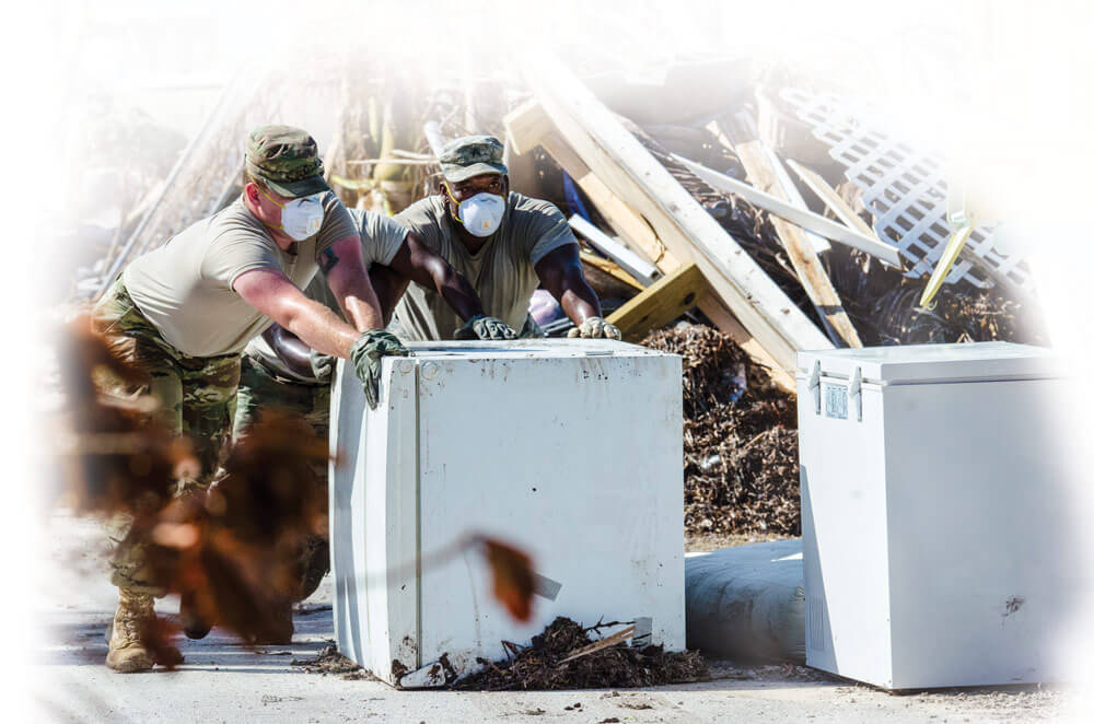 Army PFC Cody Hughes (left) and team leader SGT Robert Brown with the 753rd Brigade Engineer Battalion’s Company B remove a refrigerator with weeks- old food from a Marathon, Fla., home left devastated by Hurricane Irma.