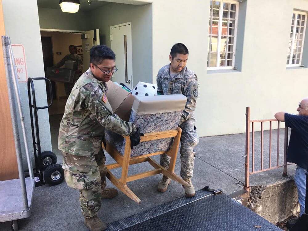 SPC Mike Nolasco (left) and SPC Gabriel Retana of the 340th Brigade Sustainment Battalion, California Army National Guard, carry furniture and equipment into a loading van at the Sonoma Developmental Center.