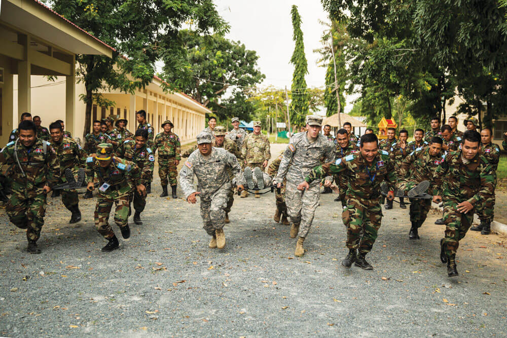 SGT Raymond Montes (left) and CPT Robert J. Taylor (center left) run with other members of the Idaho National Guard transporting a patient in a stretcher race against soldiers of the Royal Cambodian Armed Forces.