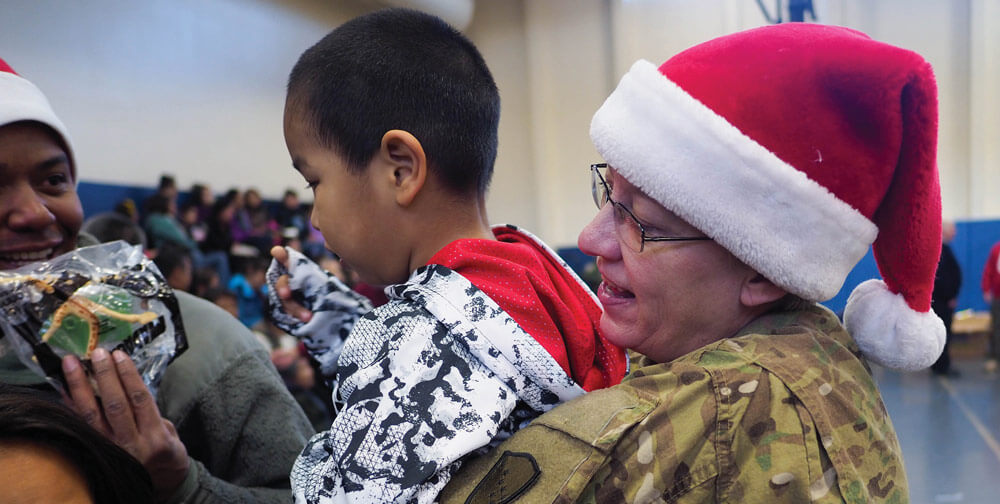 BG Laurie Hummel, Adjutant General of the Alaska National Guard, helps 4-year-old Angelo Pasitnak pick out presents at Akiachak School during Operation Santa Claus in Western Alaska.