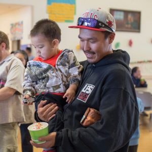 An Akiachak father and son enjoy an ice cream sundae in the Akiachak School gym