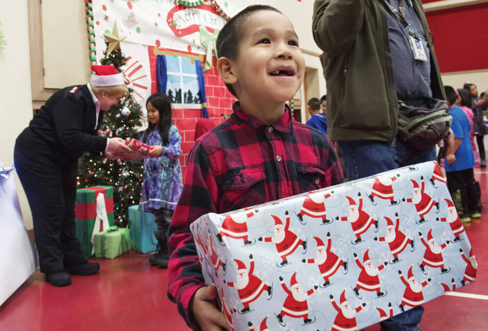 A child from St. Mary’s, Alaska, walks away smiling after receiving his gift during Operation Santa Claus 2015.