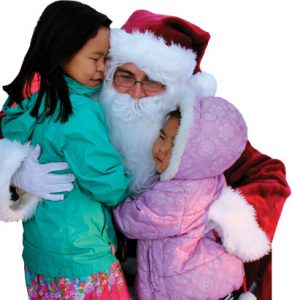 Santa gives a hug to two young sisters at Operation Santa Claus 2016.