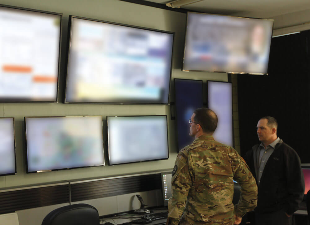 COL John Branch, commander of the 780th Military Intelligence Brigade (Cyber) is briefed by Daniel Yeager, a cyber support technician for the Indiana National Guard, on the capabilities of a Cyber Operations Center used in support of tactical and cyber operations.