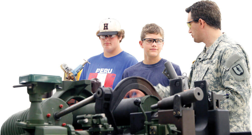 CW2 Matthew Tormey talks with students Will Hoffmann and Aaron Porter about the mechanics of the M119A2 105mm Lightweight Towed Howitzer.