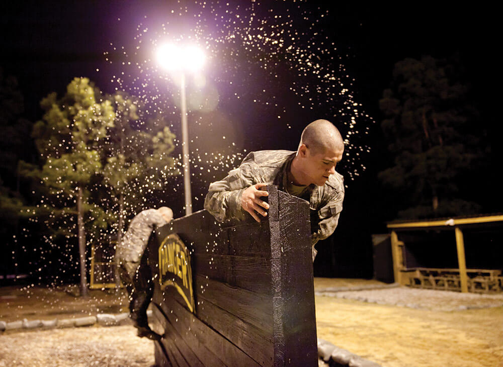 1LT Ryan King, Pennsylvania Army National Guard, moves over a six-foot wall following a water obstacle at Kirby Field. U.S. Army Maneuver Center of Excellence photo by Ashley Cross.