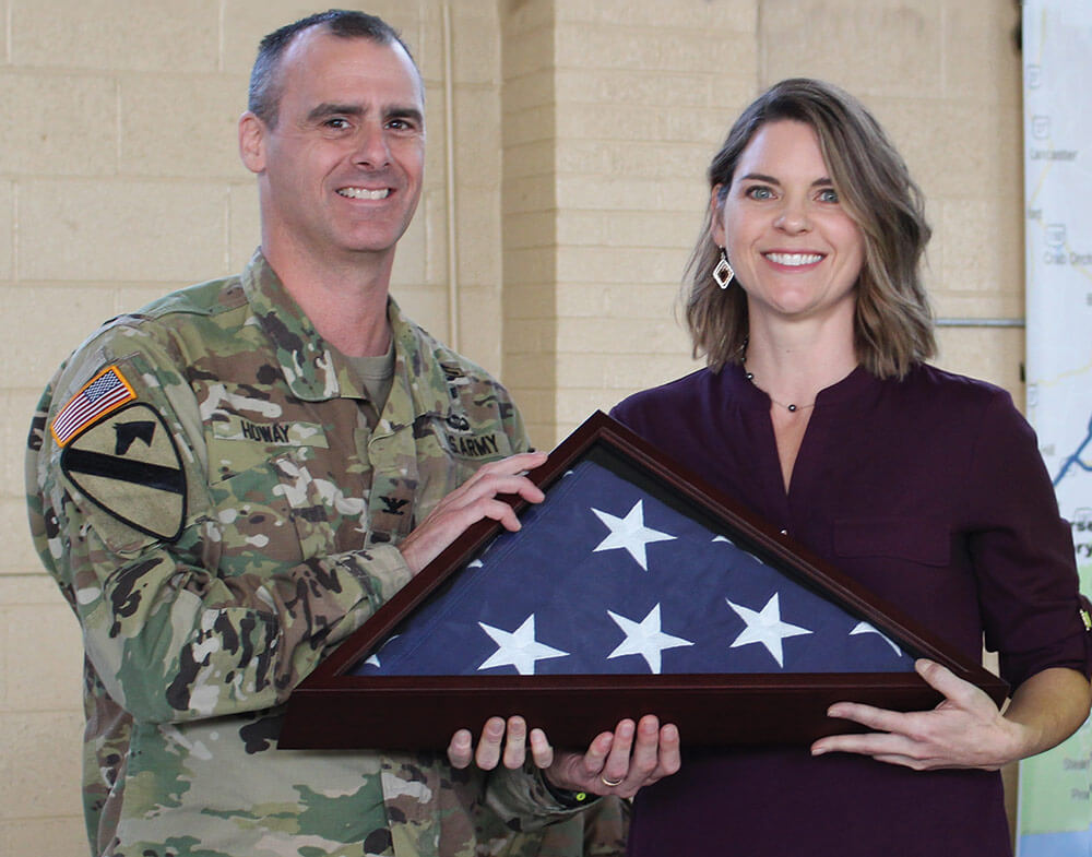 COL Bryan Howay of the Kentucky Army National Guard presents Christi Cole with the memorial flag that was carried throughout the 202-mile Mountain Warrior Memorial Ruck March. Kentucky Army National Guard photo by Stacy Floden.