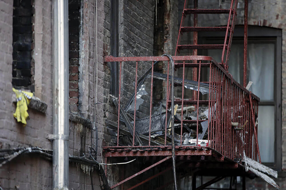 Charred items sit on the burnt-out fire escape of the New York City apartment building where PFC Emmanuel Mensah saved the lives of four people during a deadly fire that broke out in the building on Friday, Dec. 29, 2017. AP Photo by Julio Cortez.