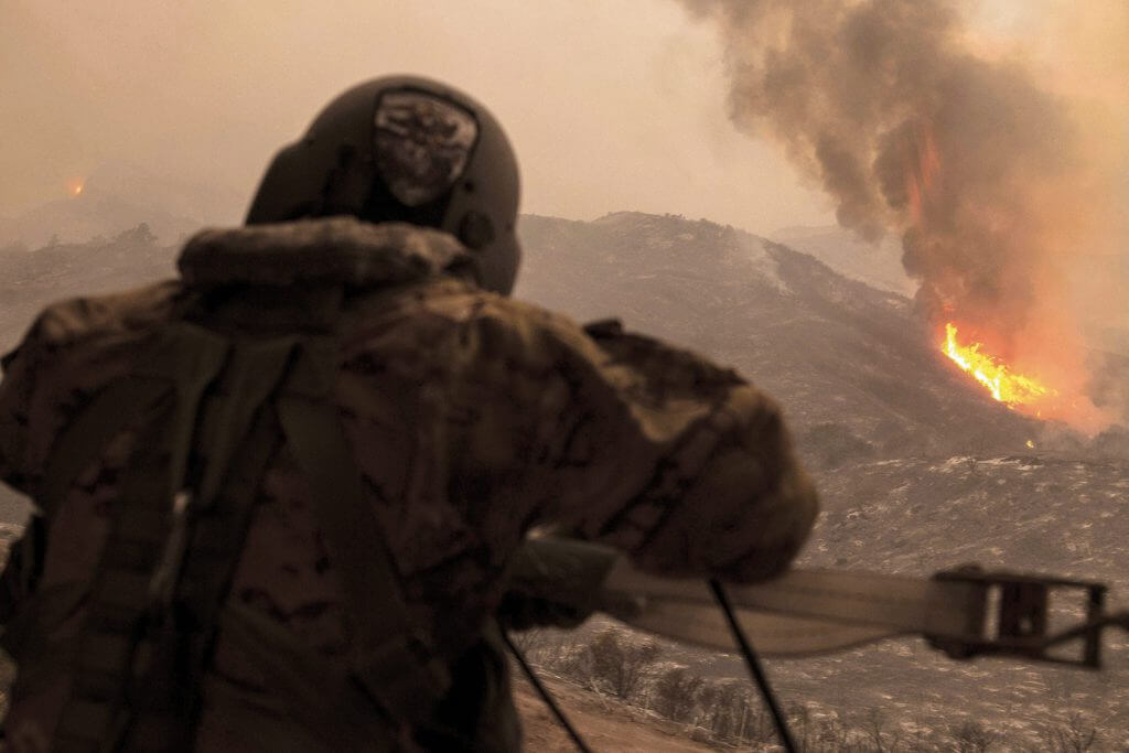 SGT Anthony Orduno, a UH-60 Black Hawk helicopter crew chief for the California Army National Guard, takes stock of the Thomas Fire as he and the rest of the Black Hawk crew spend the day fighting the blaze on Dec. 9, 2017. At the time, 30 helicopters, 575 engines and 3,993 people from various organizations were fighting the flames. The Thomas Fire would go on to burn more acres than any fire in modern California history. California National Guard photo by SrA Crystal Housman