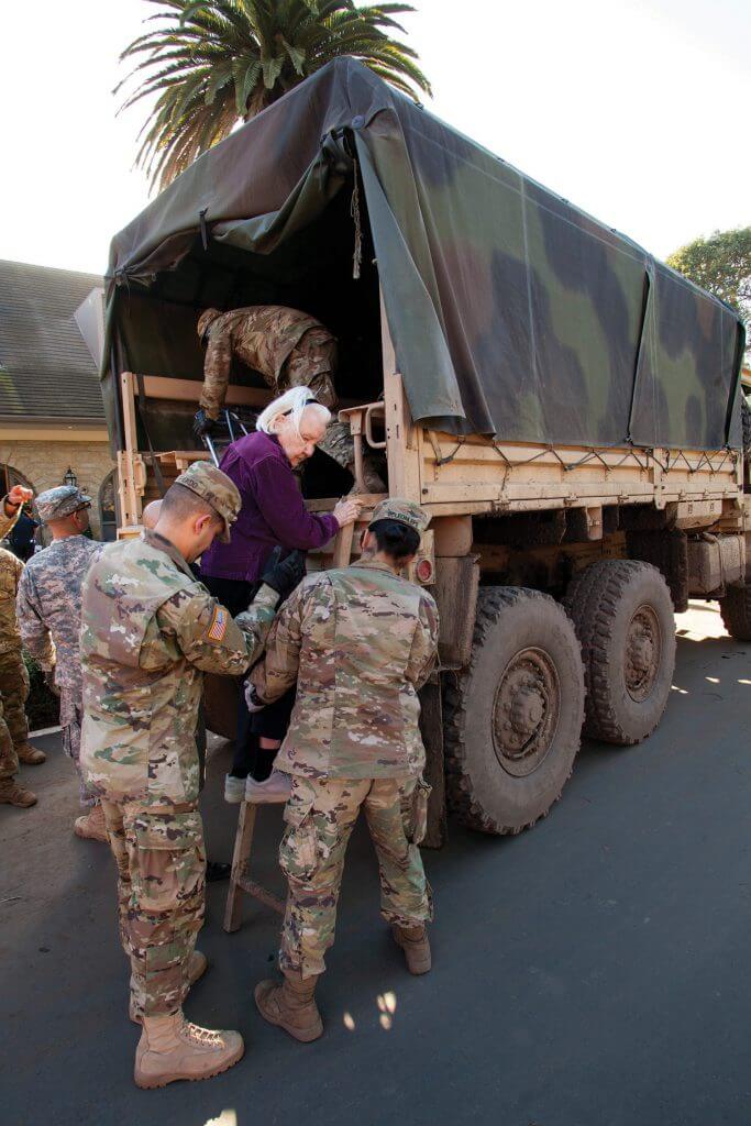 Soldiers from the California National Guard’s 1114th Composite Transportation Company help a 90-year-old woman climb up a ladder and into the back of their light medium tactical vehicle (LMTV) after evacuating the woman from her Montecito, Calif., neighborhood to a centralized drop-off point, Jan. 11, 2018. Massive mudslides left the community in ruins after soil-stabilizing vegetation was destroyed by the Thomas Fire. Heavy rains followed the blaze and caused mudslides that destroyed 73 buildings, damaged 466 buildings and killed at least 17 people. California National Guard photo by SrA Crystal Housman