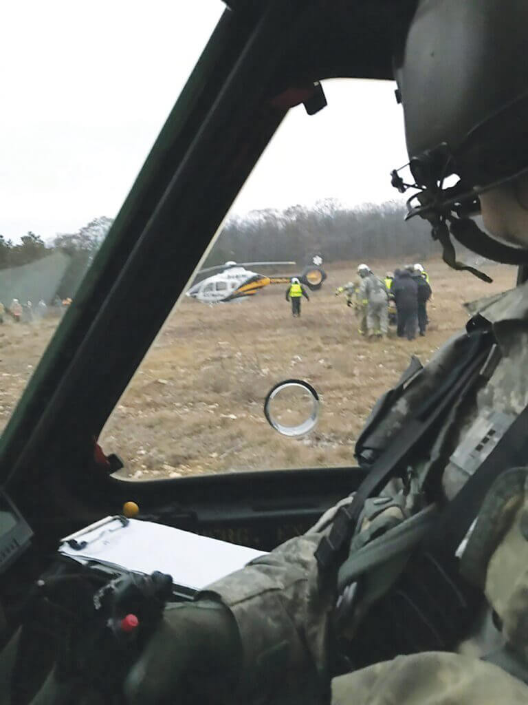 Pennsylvania Army National Guard CW3 James Menoher observes first responders transporting a patient that he and other members of the Pennsylvania Helicopter Aquatic Rescue Team rescued moments before. Photo courtesy of the Pennsylvania Army National Guard