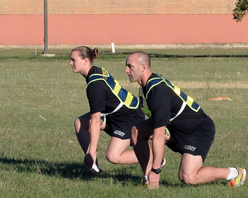 Master Fitness Trainer Course instructors SSG Sara Elkins and SFC Athan Schindler demonstrate shuttle runs during a round of exercises on the parade field at Camp Mabry as part of the Master Fitness Trainer Course.