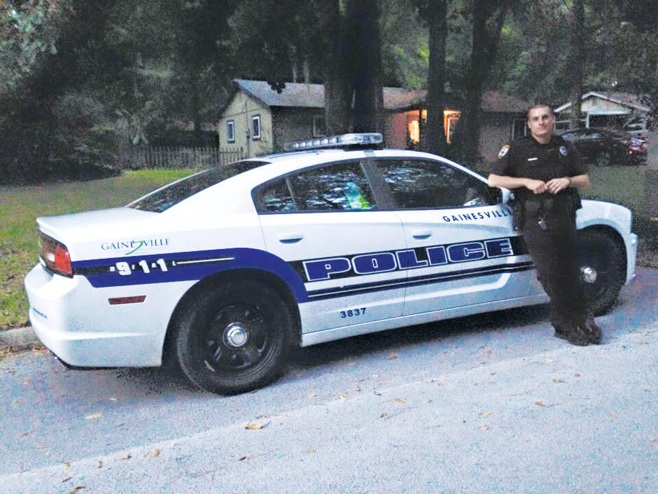 CPT Ryan Quinn with his police cruiser as he goes in for his first day back to work with the Gainesville Police Department after returning from deployment on the African continent.