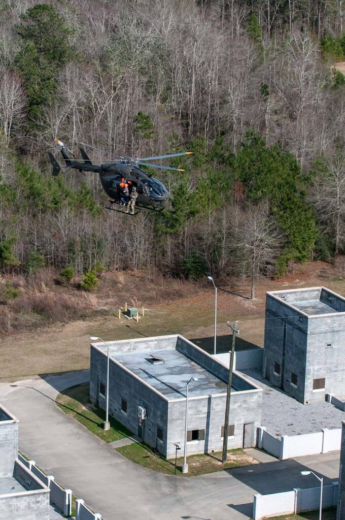 A South Carolina Army National Guard UH-72 Lakota helicopter crew hovers over buildings at the Combined Arms Combat Training Facility on Camp Shelby as members of the South Carolina Helicopter Aquatic Rescue Team hoist a simulated natural disaster victim from a rooftop during Patriot South 2018. Ohio National Guard photo by TSgt Nic Kuetemeyer