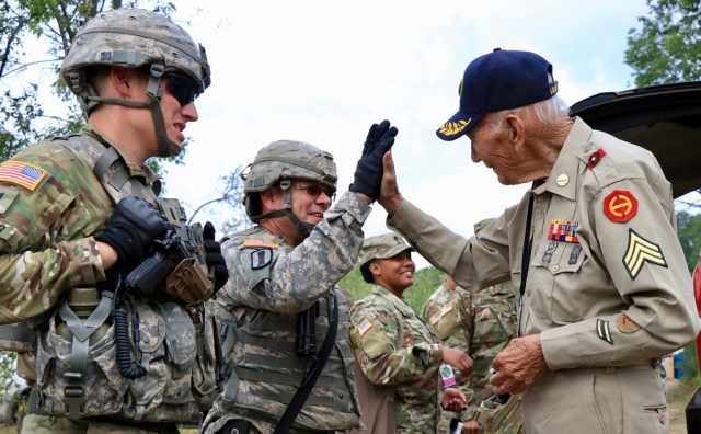 World War II Veteran Claude Cawood gives 1SG Jeffery Lemire, Battery A, 1st Battalion, 103rd Field Artillery Regiment, Rhode Island Army National Guard, a high-five after firing the M777 Howitzer this past August at Camp Grayling, Mich. Cawood, who served three years in the Philippines and was a former section chief on the M105 Howitzer, took the opportunity to visit Soldiers supporting the Northern Strike 2018 exercise. Iowa Army National Guard photo by 1SG Sara Robinson