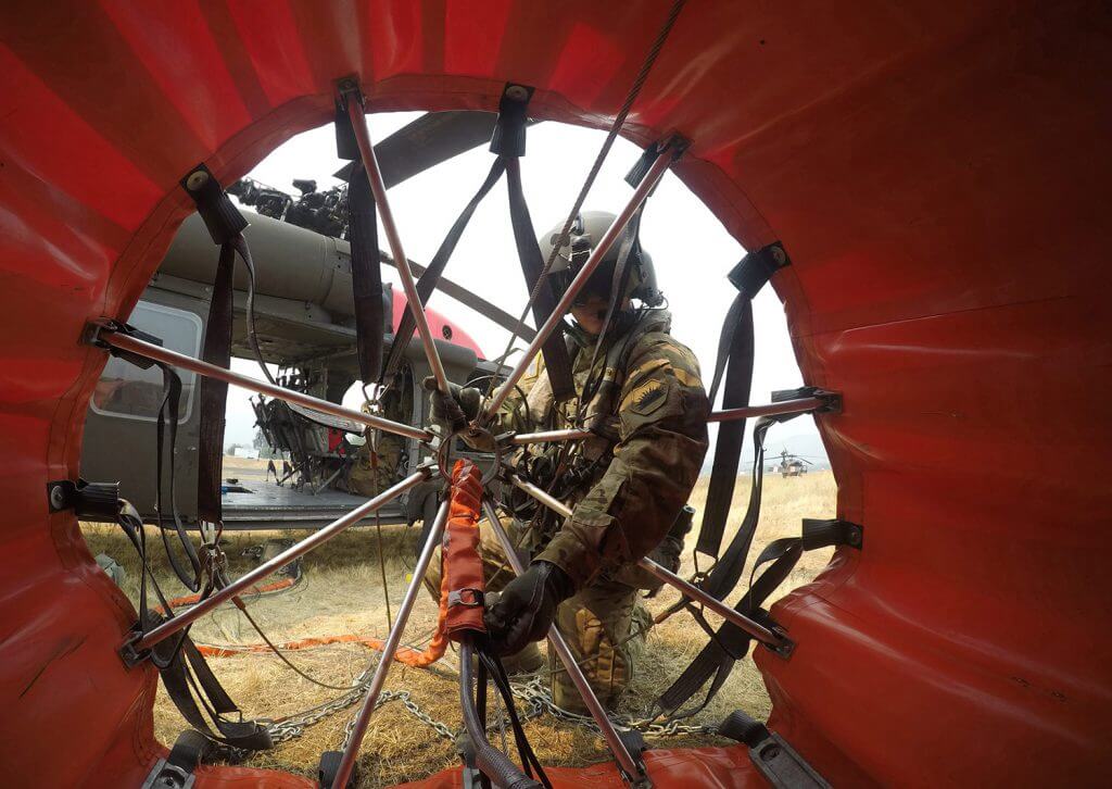 SSG Ge Xiong, UH-66 Black Hawk crew chief for the California Army National Guard’s Alpha Company, 1106th Theatre Aviation Support Maintenance Group, checks his 600-gallon water bucket prior to a mission in the summer of 2018 battling the Mendocino Complex Fires in Lake, Colusa and Mendocino counties, Calif. California Army National Guard pilots used helicopters to drop close to a half-million gallons of water in just over a week as the Ranch and River fires combined to become California’s largest wildfire in State history. California Army National Guard photo by SSG Eddie Siguenza