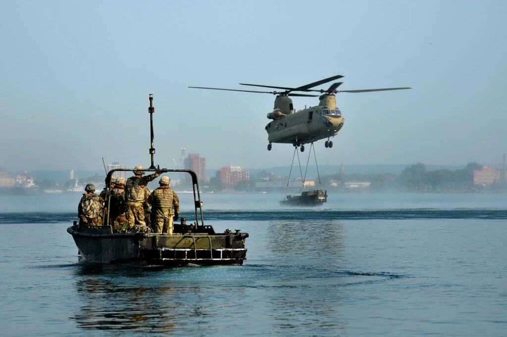 Engineers from Michigan Army National Guard’s 1437th Multi-Role Bridge Company, based out of Sault Saint Marie, Mich., wait as a Chinook from B Company, 3rd Battalion, 238th Aviation Regiment, based out of Grand Ledge, Mich., makes an aerial delivery of sling loaded components for an improved float bridge, also known as a ribbon bridge, on the St. Mary’s River. The Soldiers of the 1437th, working from 500-hp MK-II Bridge Erection Boats, maneuvered the separate pieces to rehearse the assembling of a sturdy floating bridge during a training scenario in August of this year. Michigan Army National Guard photo by SFC Helen Miller