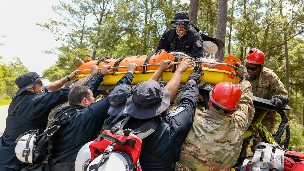 Florida civilian first responders and Florida Army National Guard Chemical, Biological, Radiological, Nuclear, and Explosive (CBRNE) Enhanced Response Force Package members prepare a mock casualty victim for transport during a Search and Rescue Exercise, May 2019. Florida National Guard photo by Ching Oettel