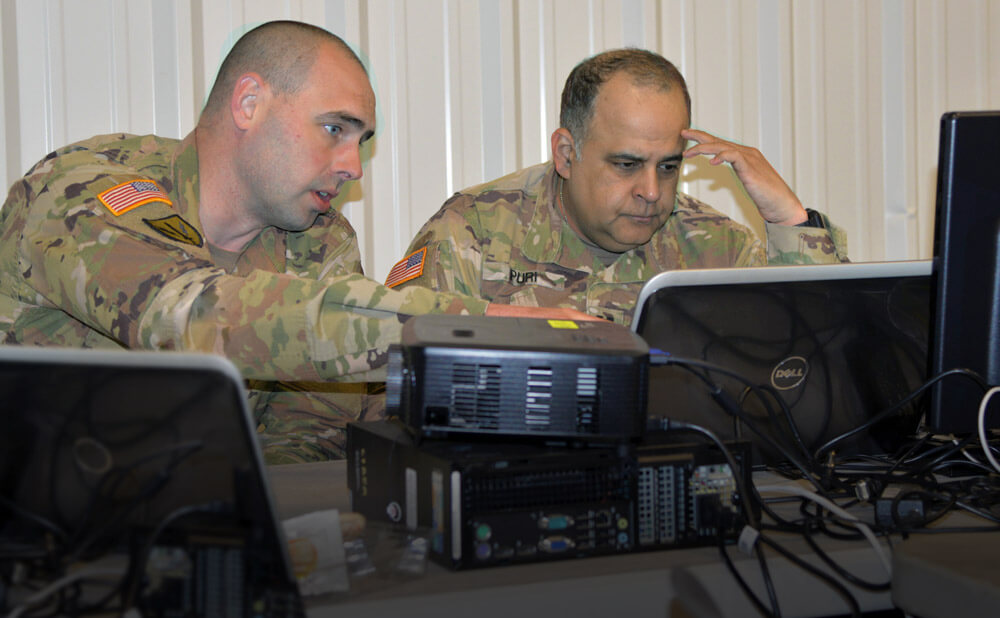 CW2 Brian Gosch (left) and CPT Sameer Puri, both members of the Washington National Guard’s Cyber Mission Assurance Team, work to identify network abnormalities during the Cyber Shield 19 training exercise held at Camp Atterbury, Ind., April 2019. Washington National Guard photo by Bradford Leighton